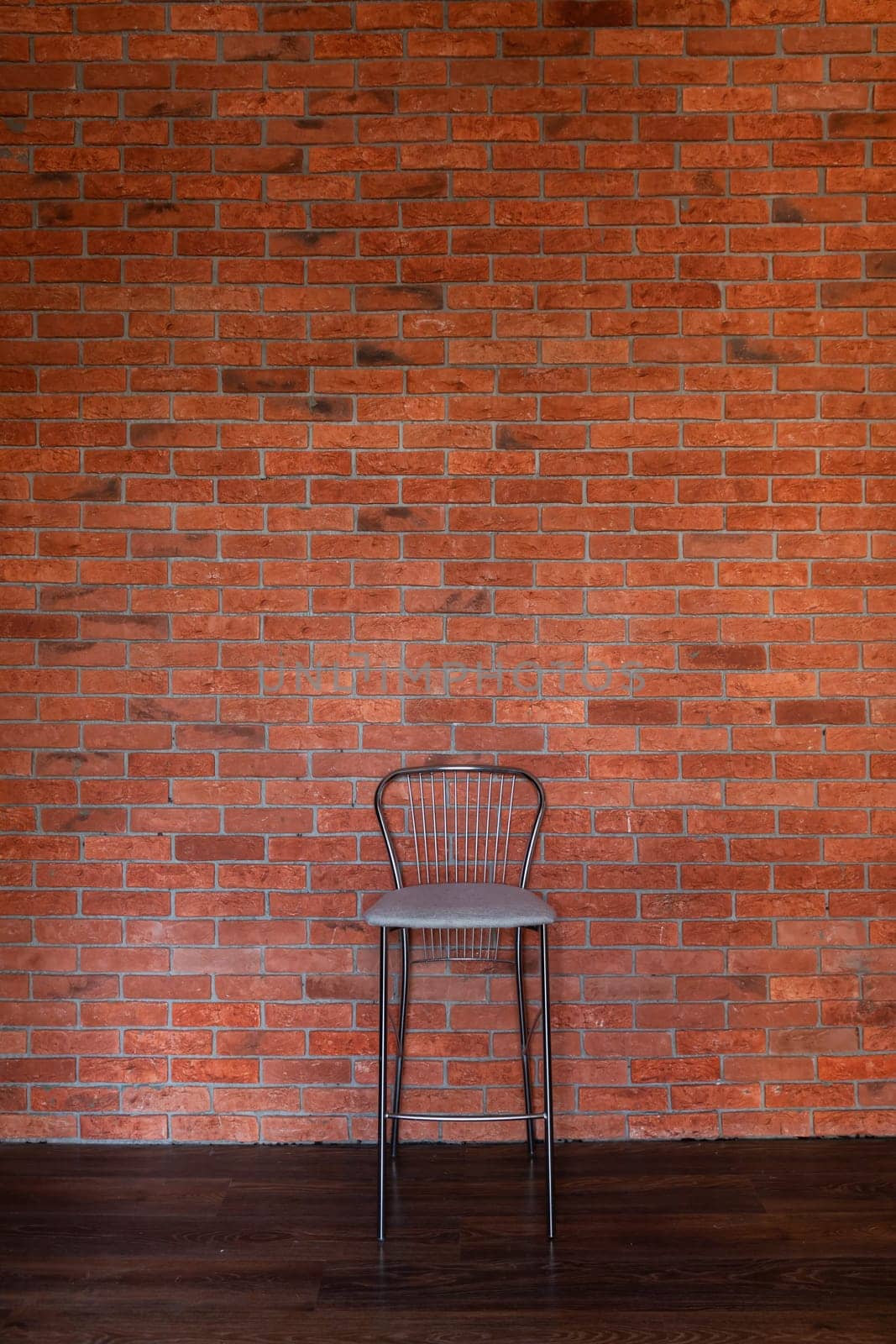 High bar stool against brick wall