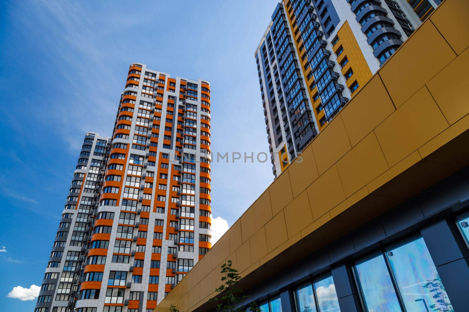 freshly built high rise apartment buildings on blue sky background with white clouds.