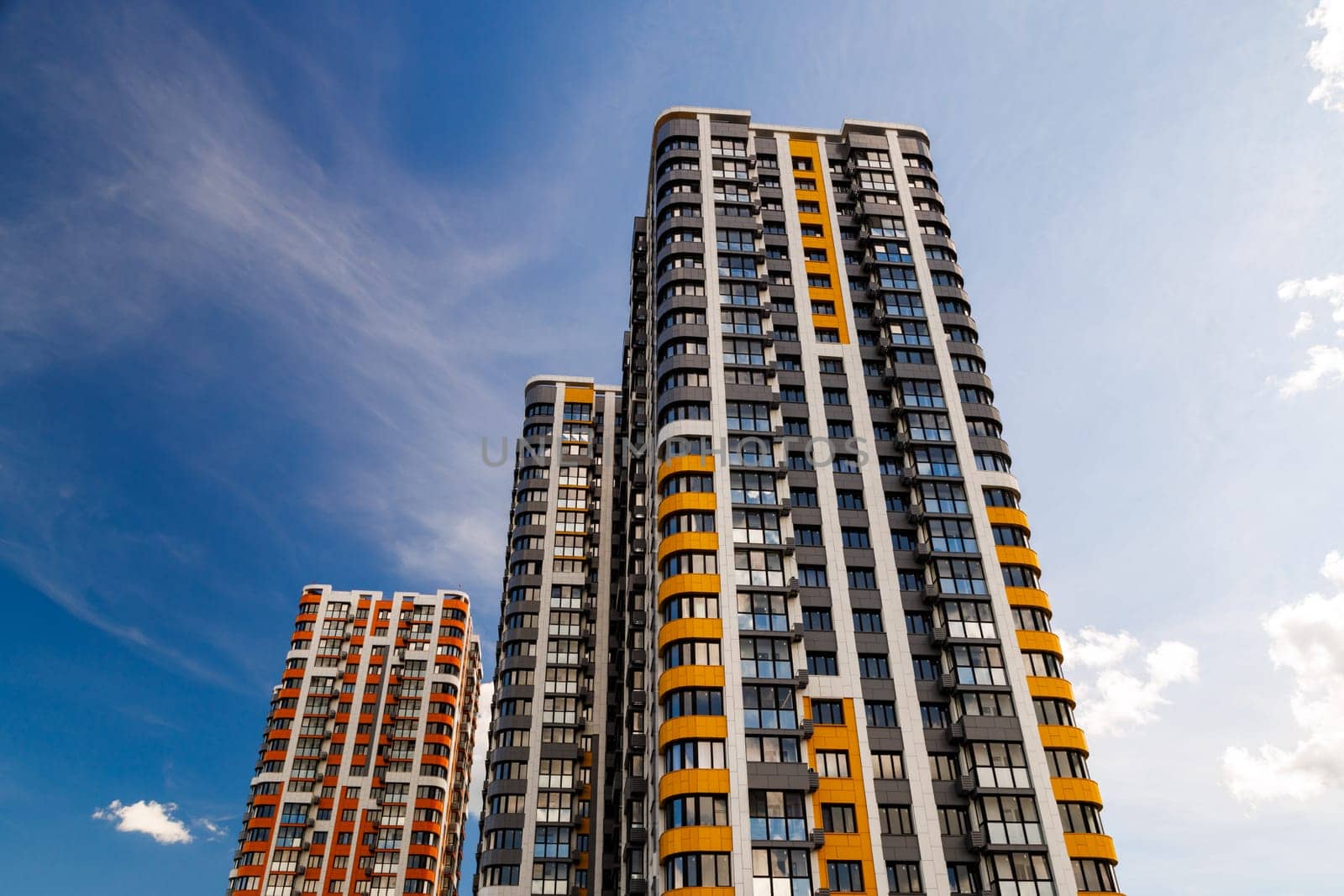freshly built high rise apartment buildings on blue sky background with white clouds.