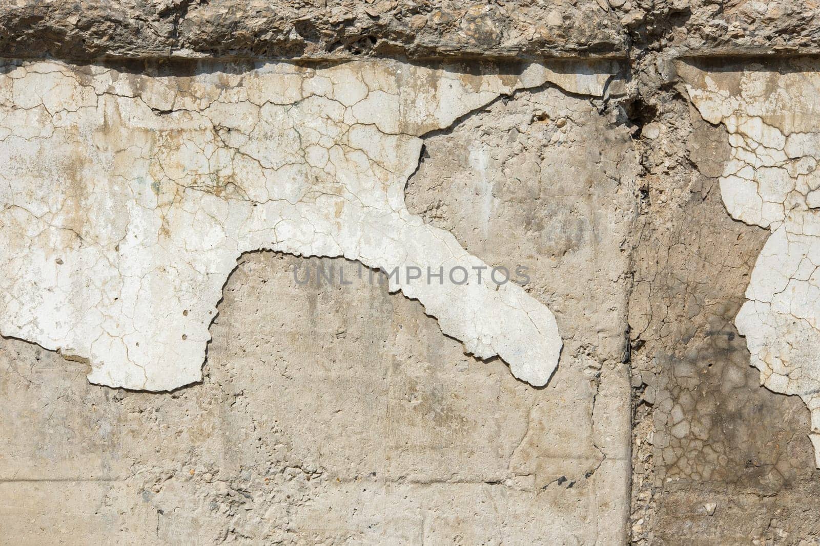 peeled off plaster on distressed concrete wall under direct sun light.