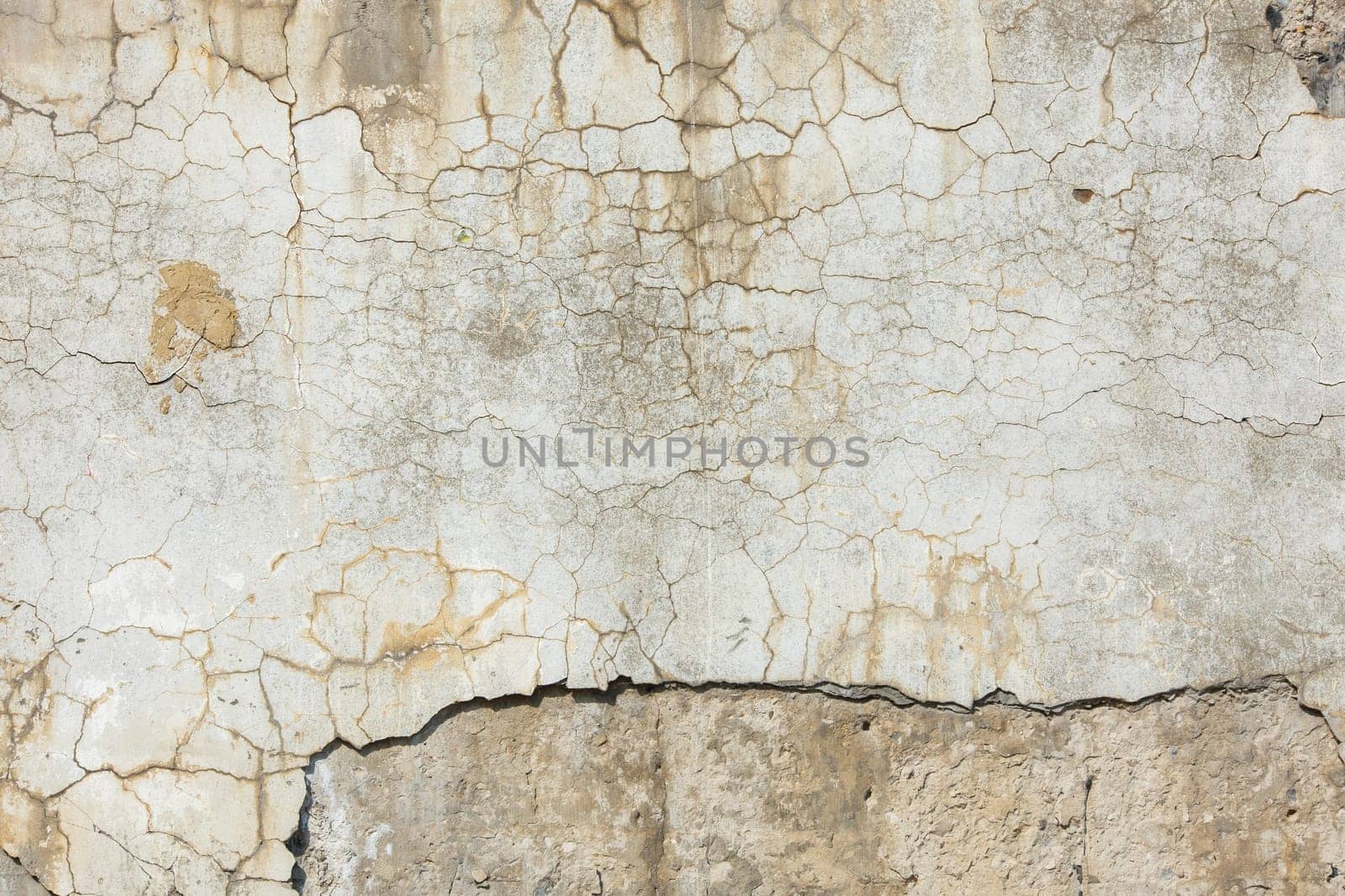 peeled off plaster on distressed concrete wall under direct sun light.