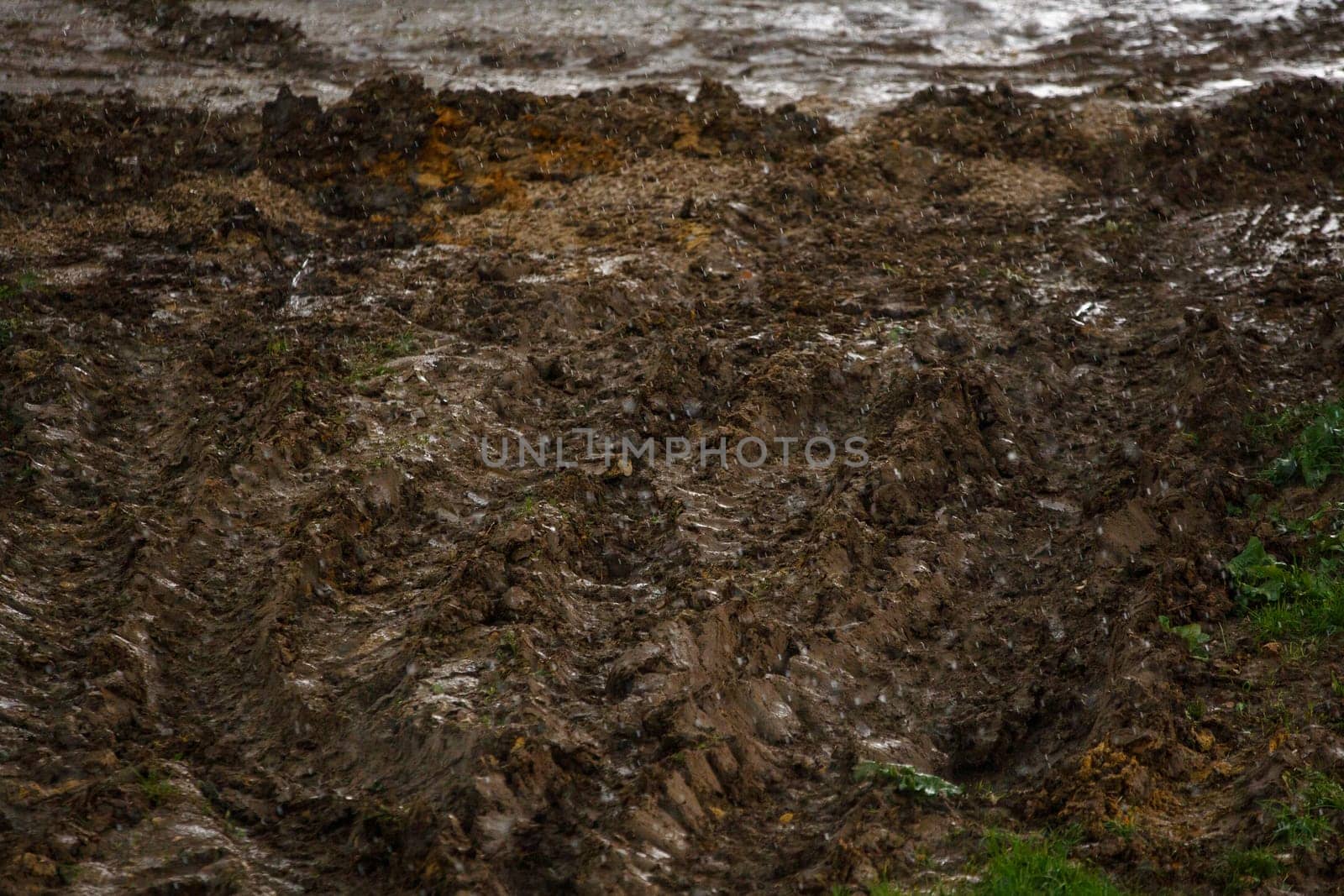 heavy vehicle tracks on dirt surface under summer rain at day light, season of bad roads