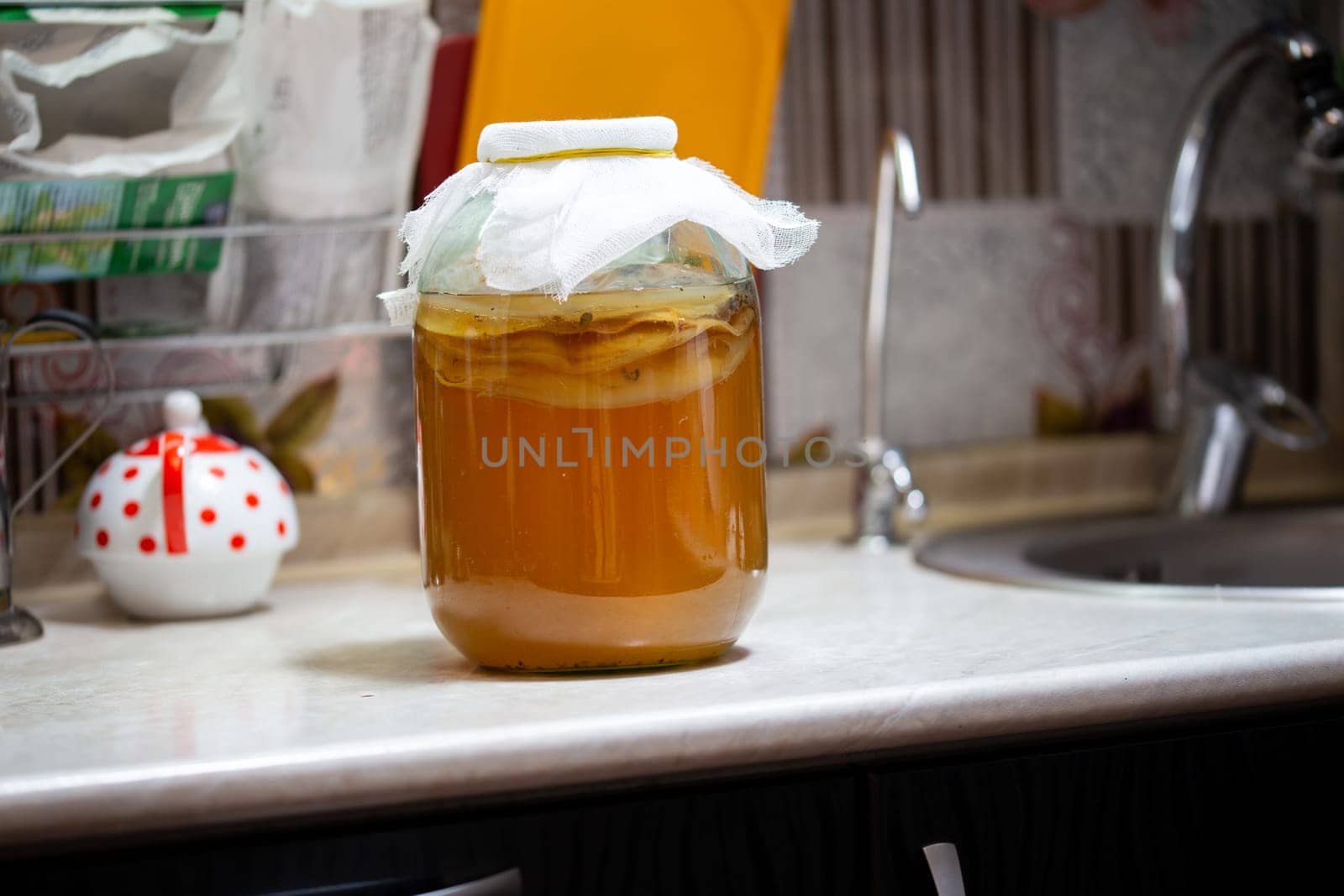 Homemade Kombucha Tea in glass jar on kitchen table - close-up with selective focus