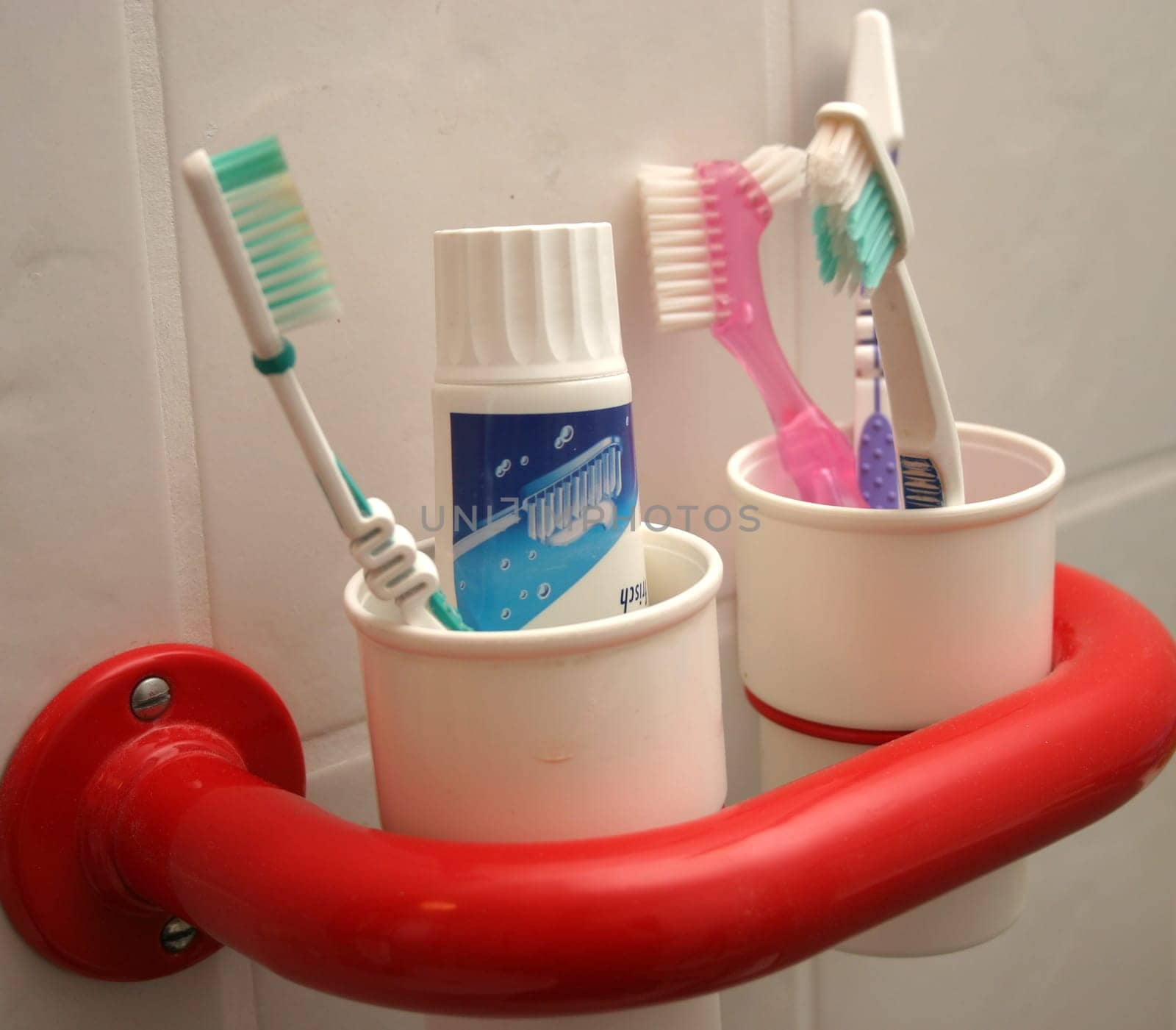 White toothbrush cups in red holder with toothbrushes
