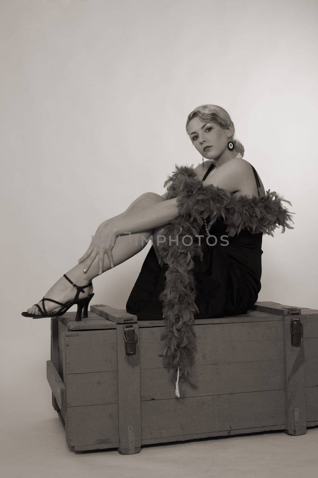 A woman dressed in the style of the 20s sits relaxed on an ammunition box