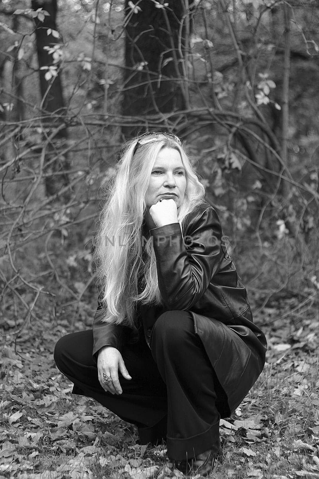 Woman squatting in the woods and looking into the distance