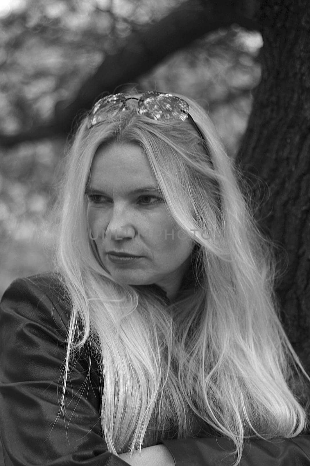 Portrait photo of a woman leaning against a tree