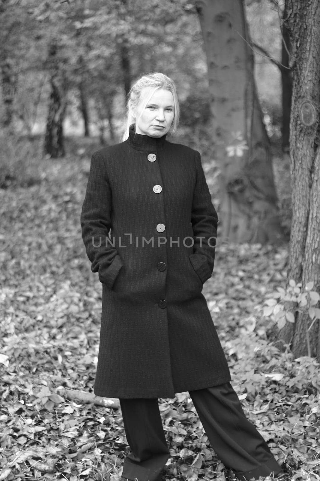 A woman stands in the forest and looks grimly into the camera