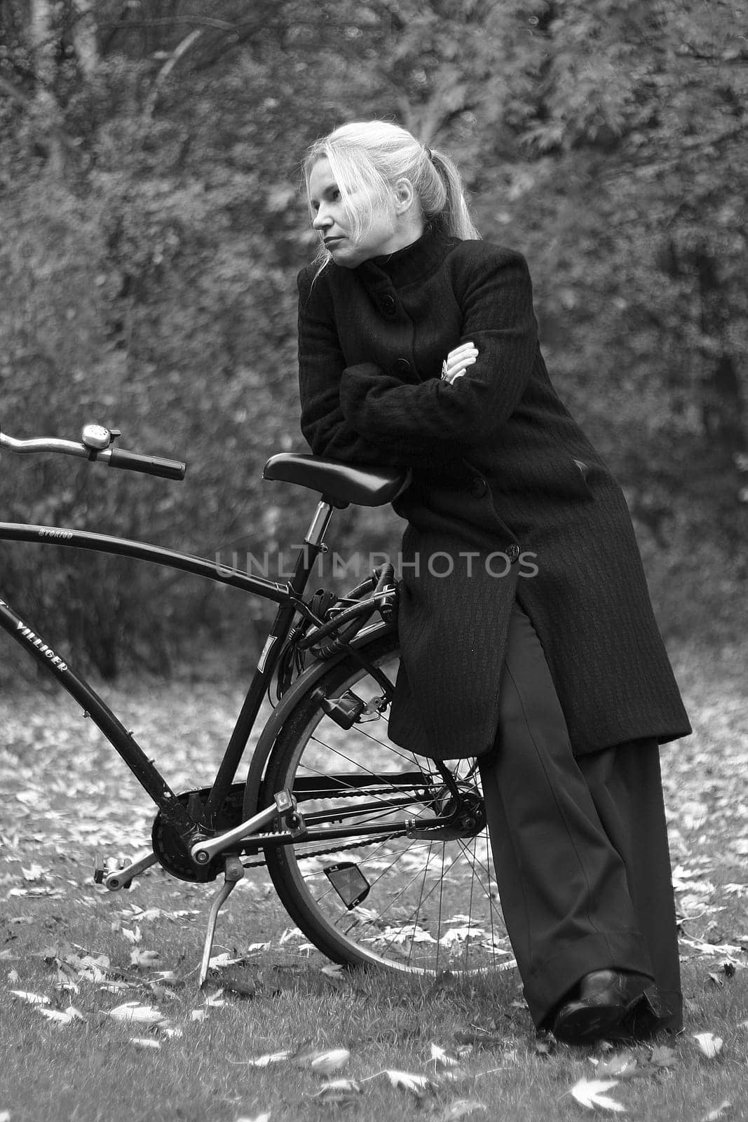 Black and white photo shows a woman with a bicycle in the herst
