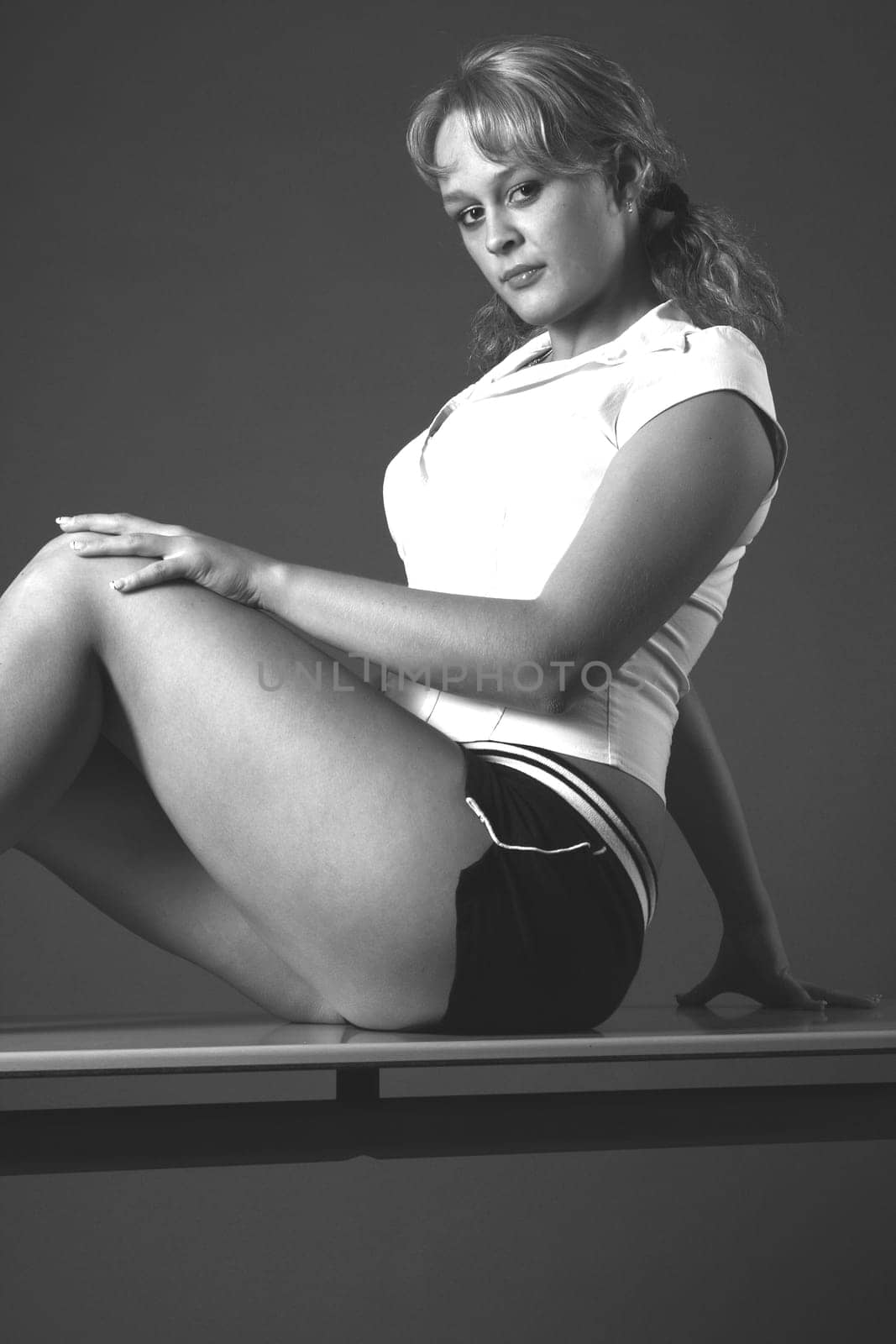 Woman sitting on desk in sports dress,smiling