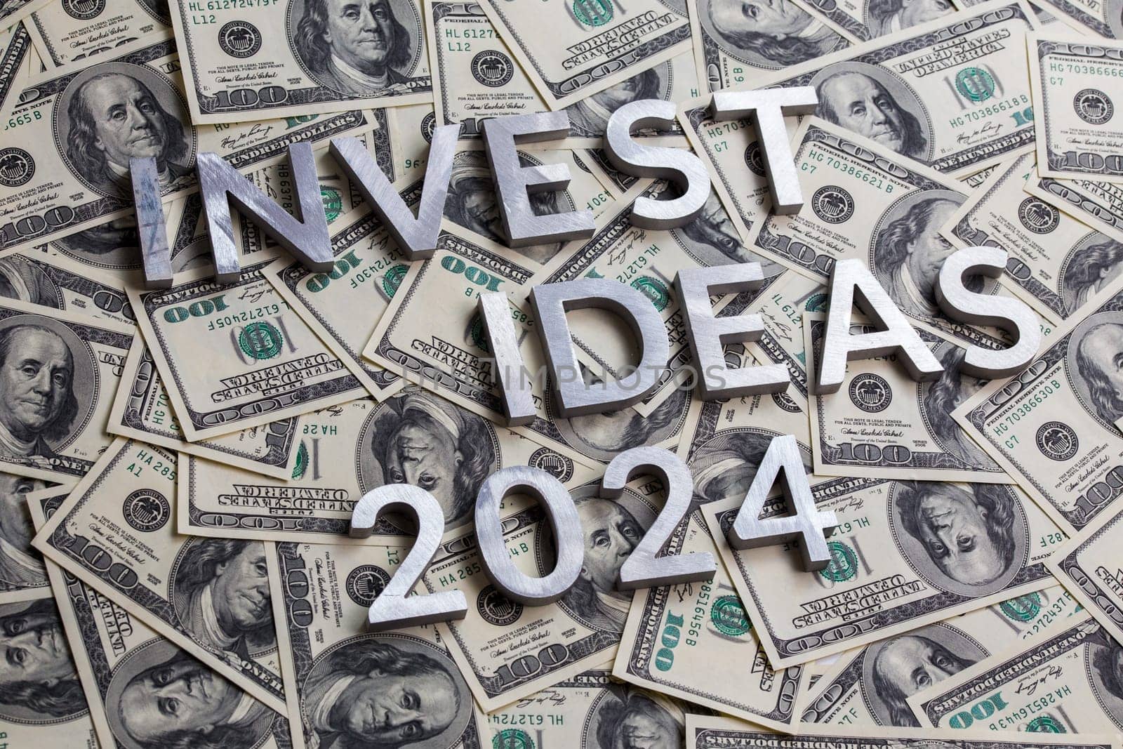 words invest ideas 2024 laid with thick metal letters on the US dollar bills background - with selective focus and diagonal composition. by z1b