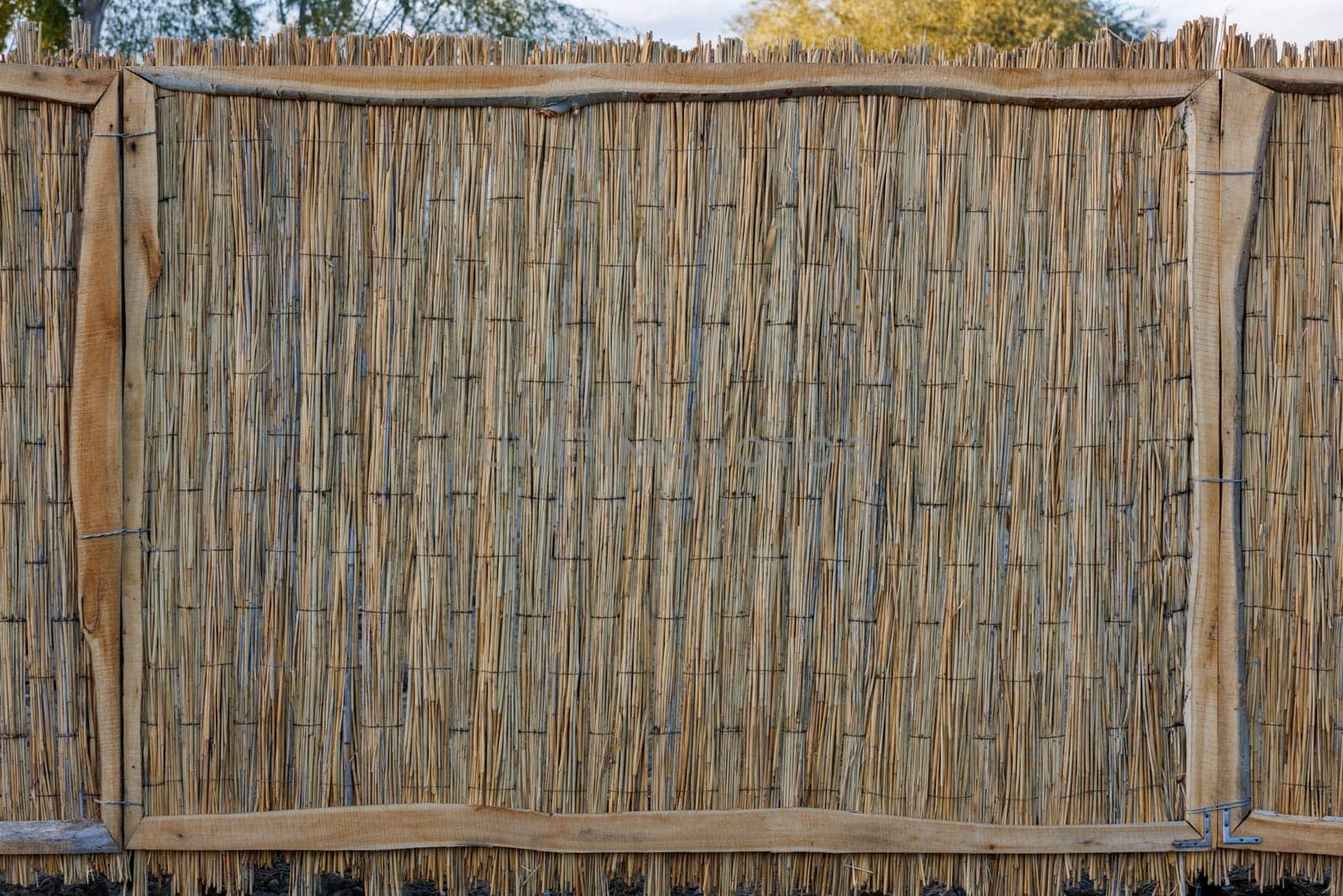 rustic fence made of wicker straw mat.