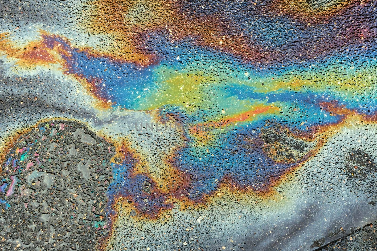 Colored oil stains close up, the color of the gasoline stain on the pavement road as a texture or background.