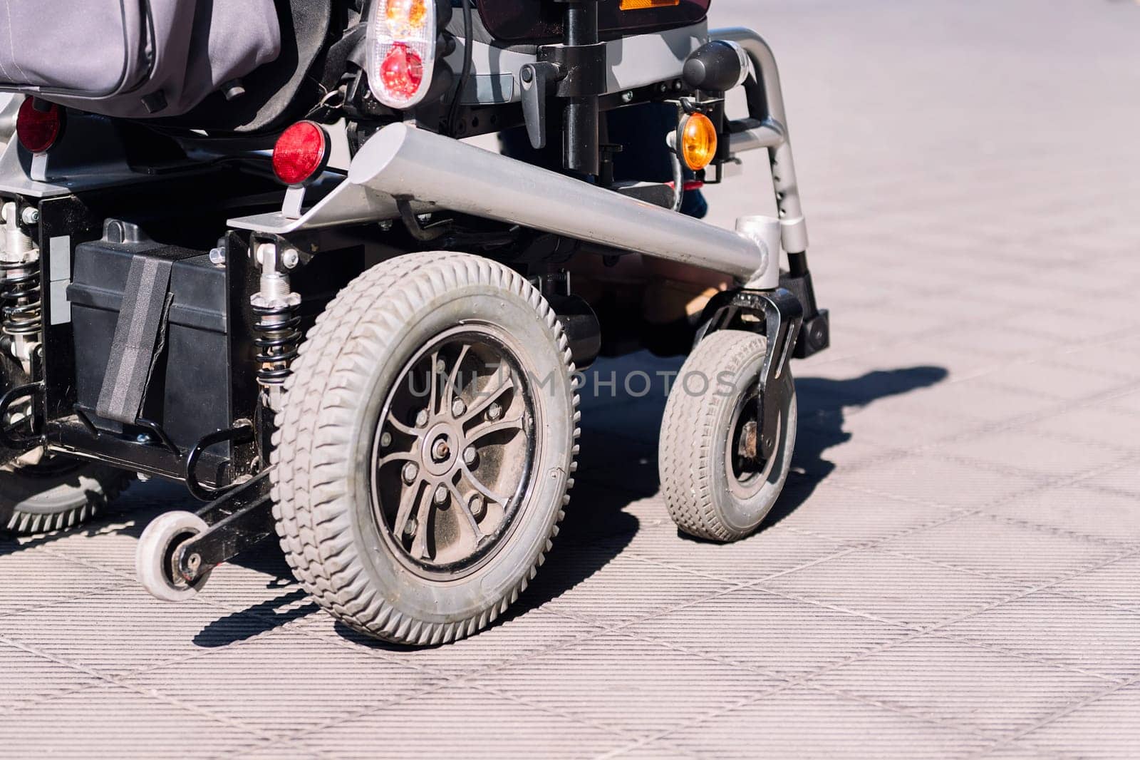 cropped photo of an electric wheelchair on a sidewalk, concept of urban mobility for people with disability, copy space for text