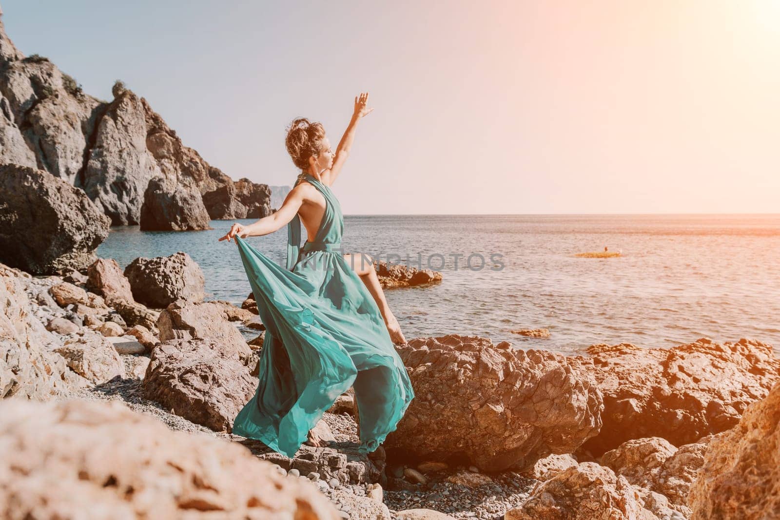 Side view a Young beautiful sensual woman with black hair in a long mint dress posing on a beach with calm sea bokeh lights on sunny day. Girl on the nature on blue sky background. Fashion photo by panophotograph