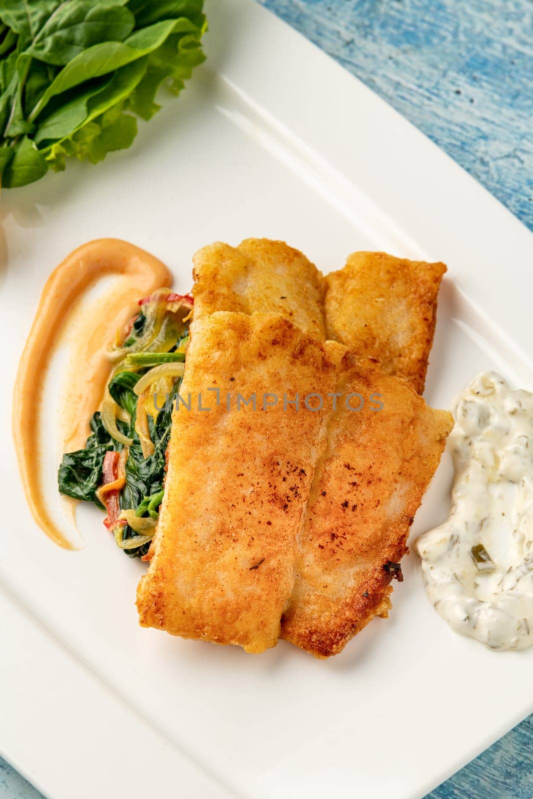 Fried Panga Fillet with greens and onions on the side and spinach underneath by Sonat