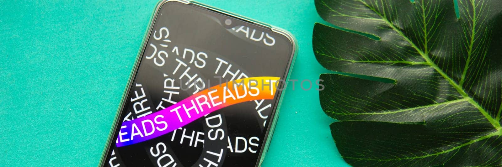 Tver, Russia - July 15, 2023, threads logo on the smartphone screen, on a green background. The threads icon. The logo of the current application. Threads social network. by Annu1tochka