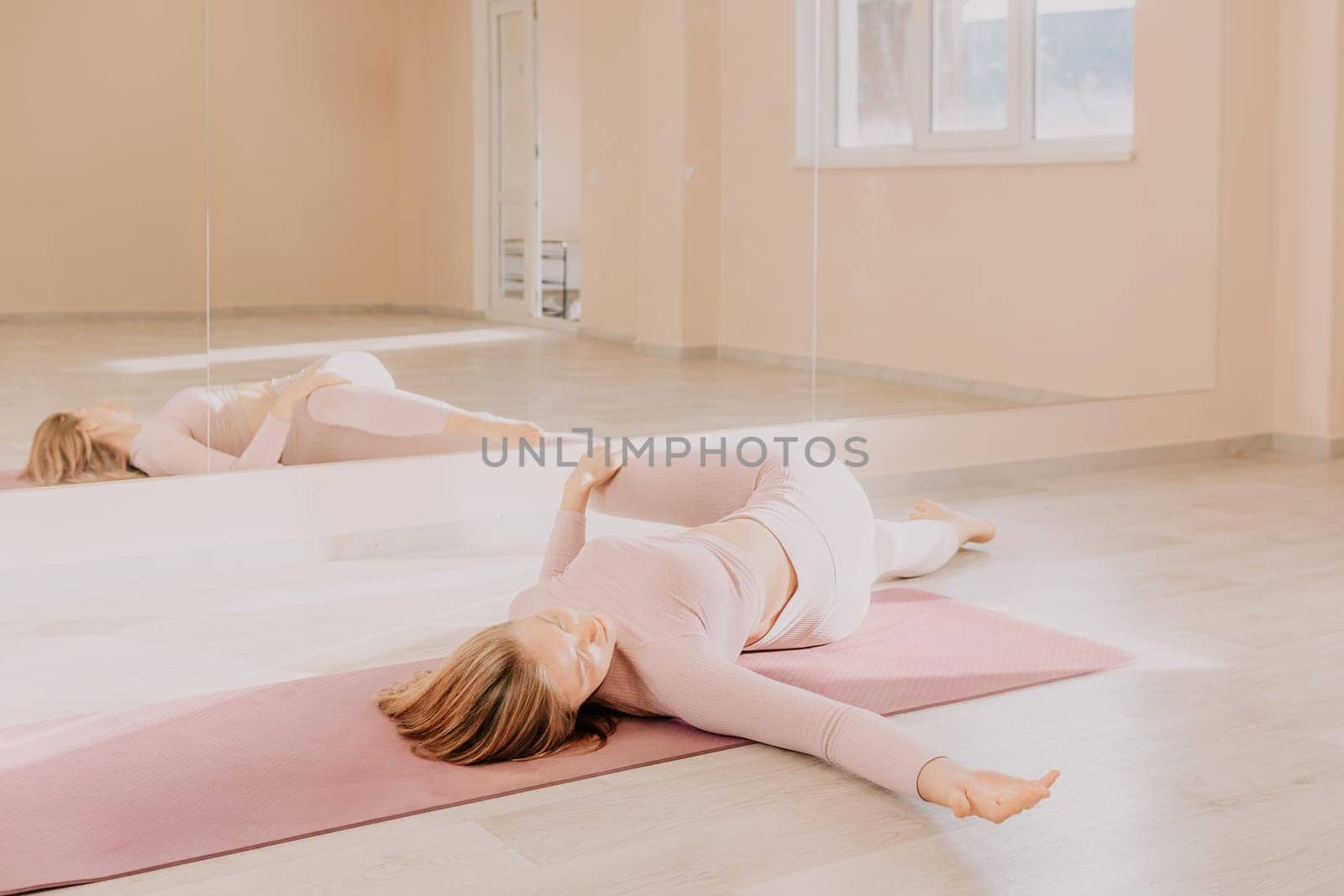 Young woman with long hair in white swimsuit and boho style braclets practicing outdoors on yoga mat by the sea on a sunset. Women's yoga fitness routine. Healthy lifestyle, harmony and meditation