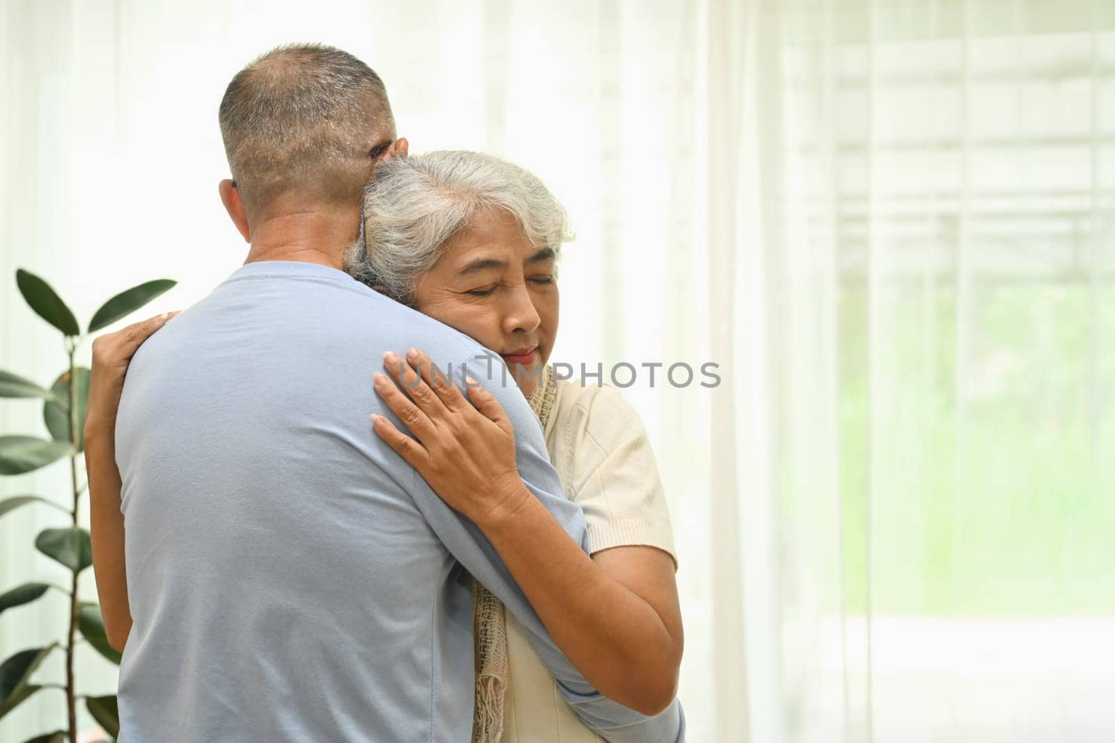 Happy senior couple hugging, bonding, enjoying wellbeing and spending free time together at home.