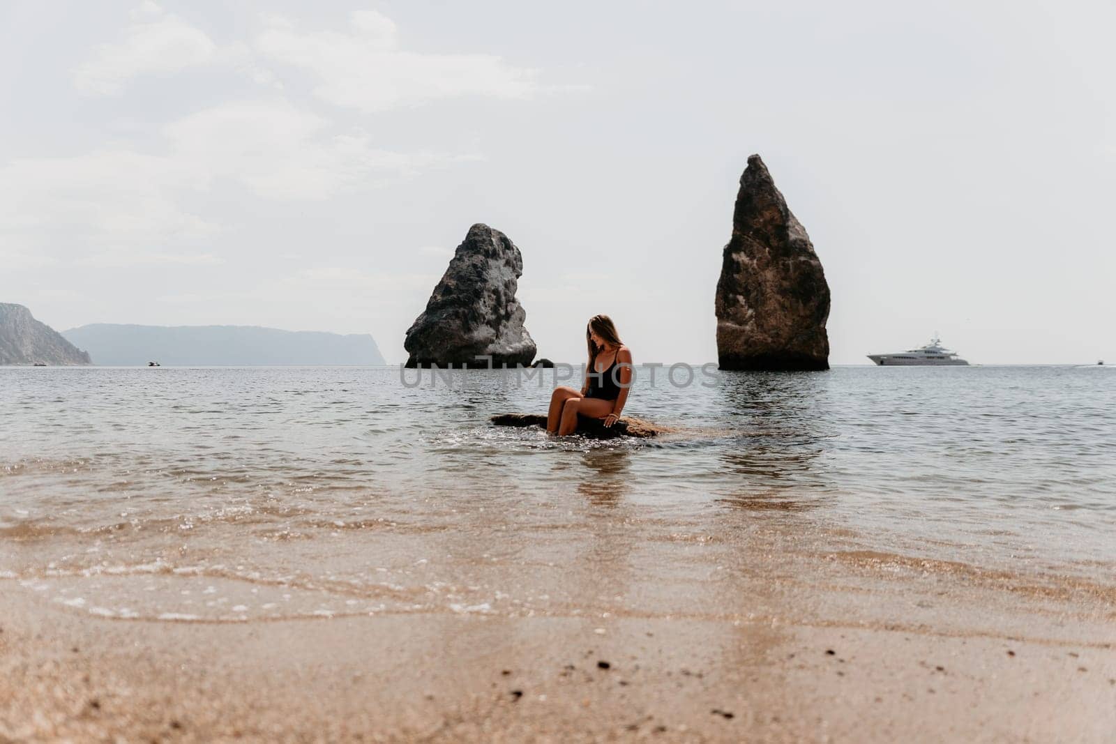 Woman summer travel sea. Happy tourist enjoy taking picture outdoors for memories. Woman traveler posing on the beach at sea surrounded by volcanic mountains, sharing travel adventure journey by panophotograph