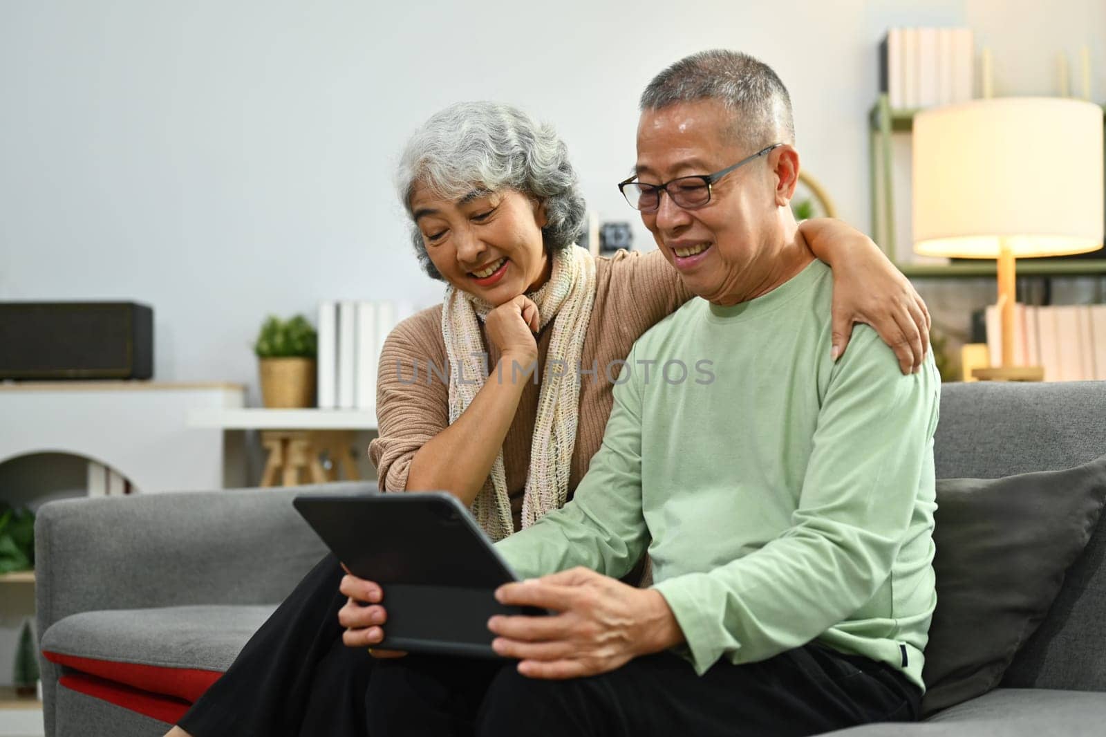 Happy senior couple using digital tablet scrolling, reading news feed in social media and browsing internet.