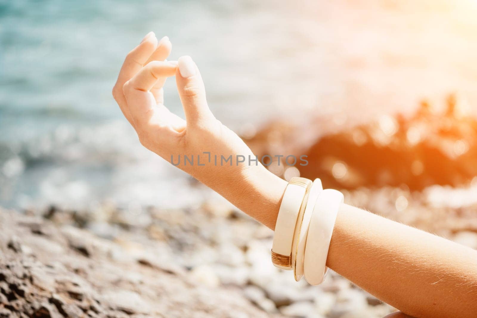 Close up Yoga Hand Gesture of Woman Doing an Outdoor meditation. Blurred sea background. Woman on yoga mat in beach meditation, mental health training or mind wellness by ocean, sea by panophotograph