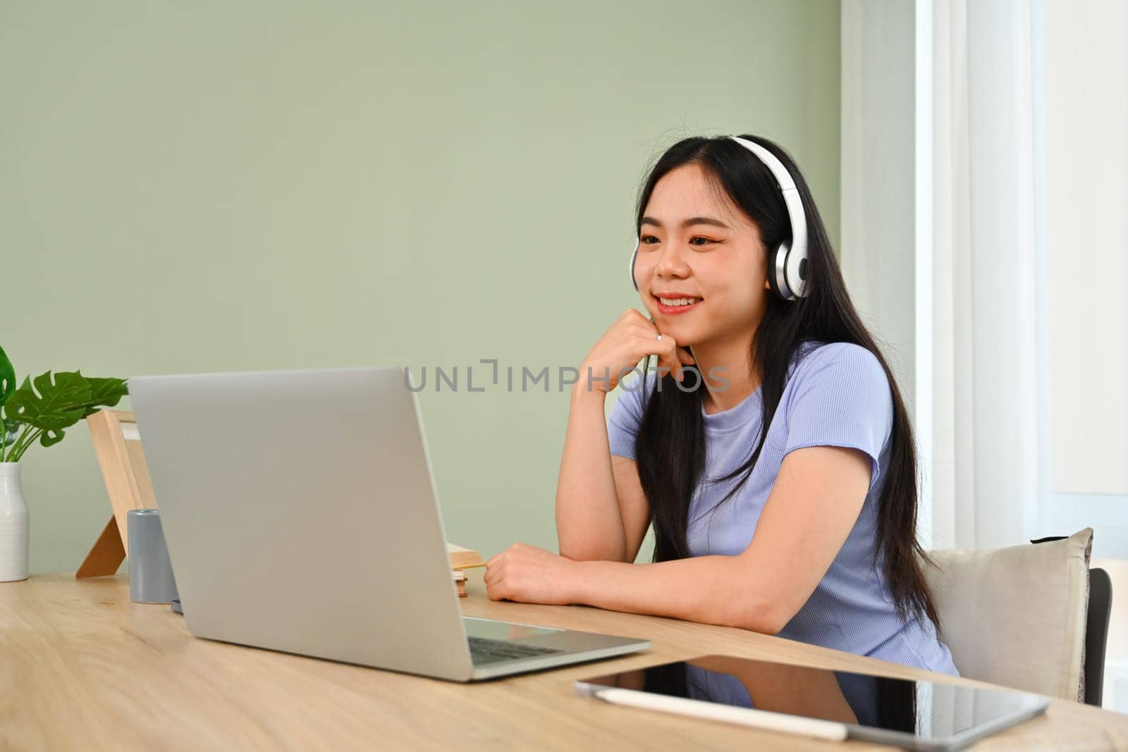 Young woman in headphone using laptop, working online, searching in internet. People and technology concept.