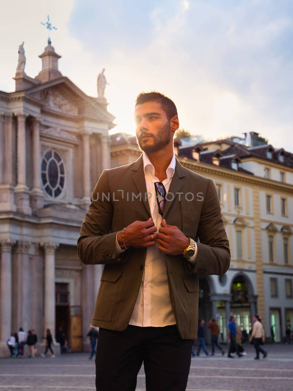A man in a suit standing in front of a church in Piazza San Carlo in Turin, Italy. A businessman standing in a bustling city street under a clear sky.