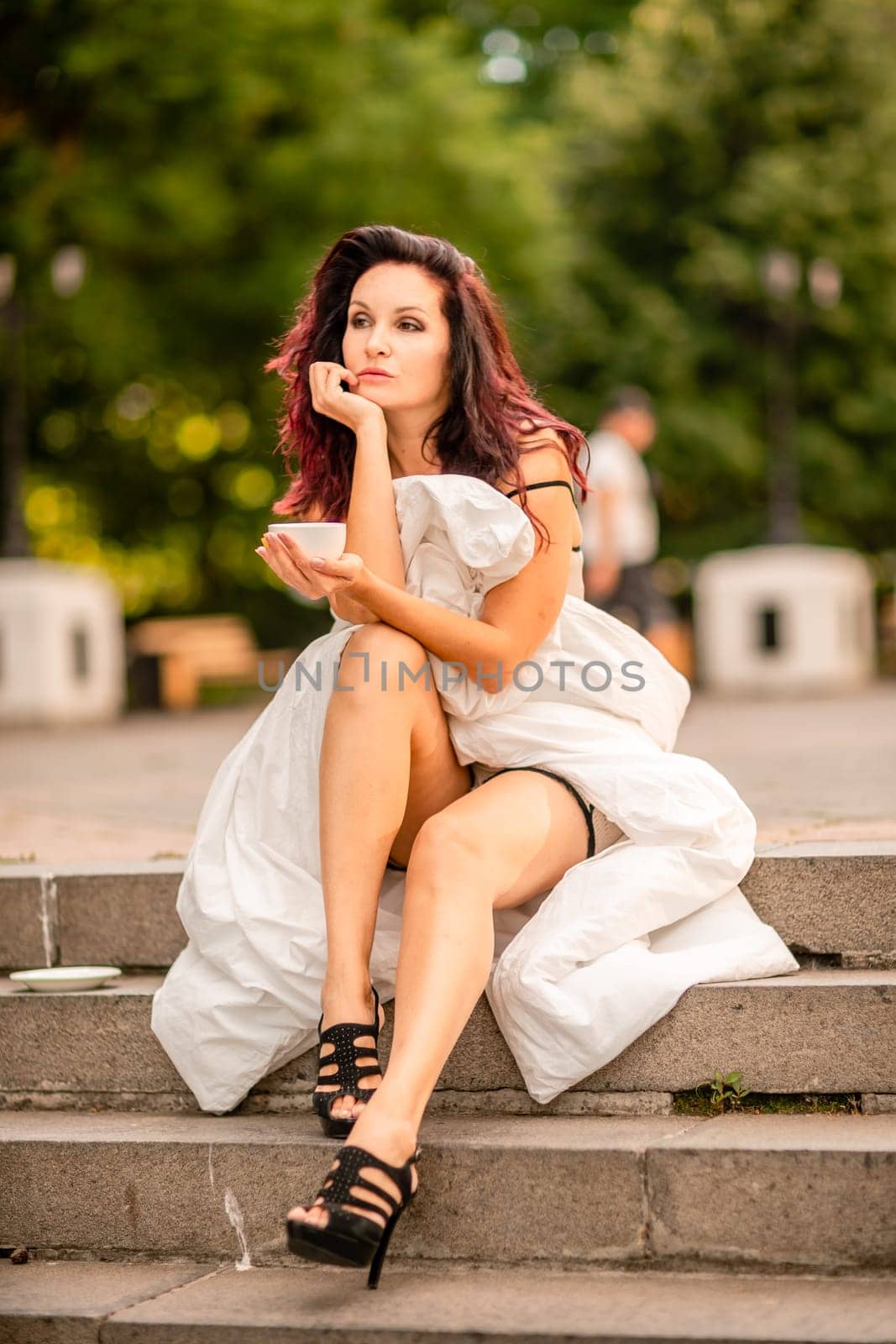 Woman city blanket. Morning in the big city. A brunette in a white blanket is enjoying a cup of tea in the city center
