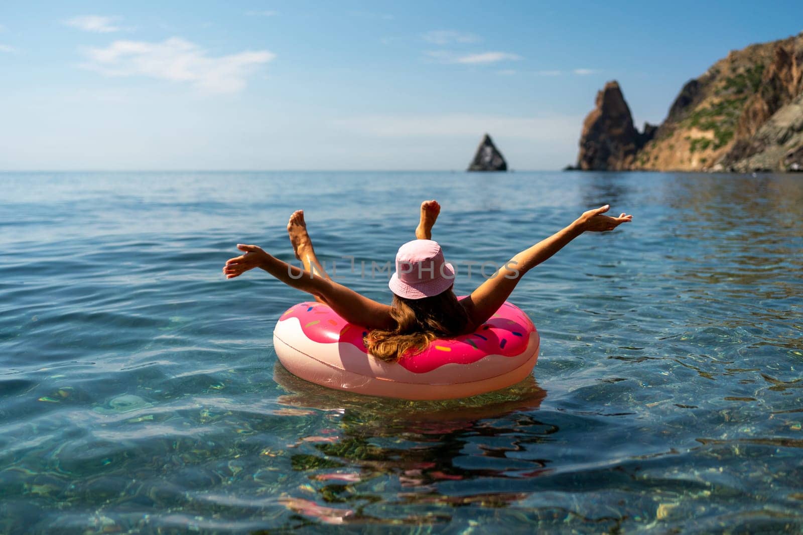 Summer vacation woman in hat floats on an inflatable donut mattress. Happy woman relaxing and enjoying family summer travel holidays travel on the sea. by Matiunina