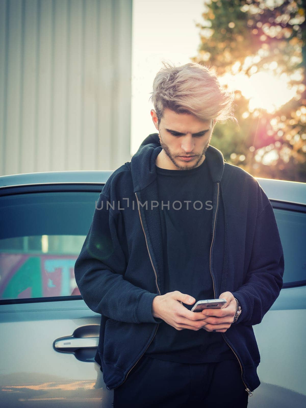 Photo of a man using his cell phone while standing in front of a car by artofphoto