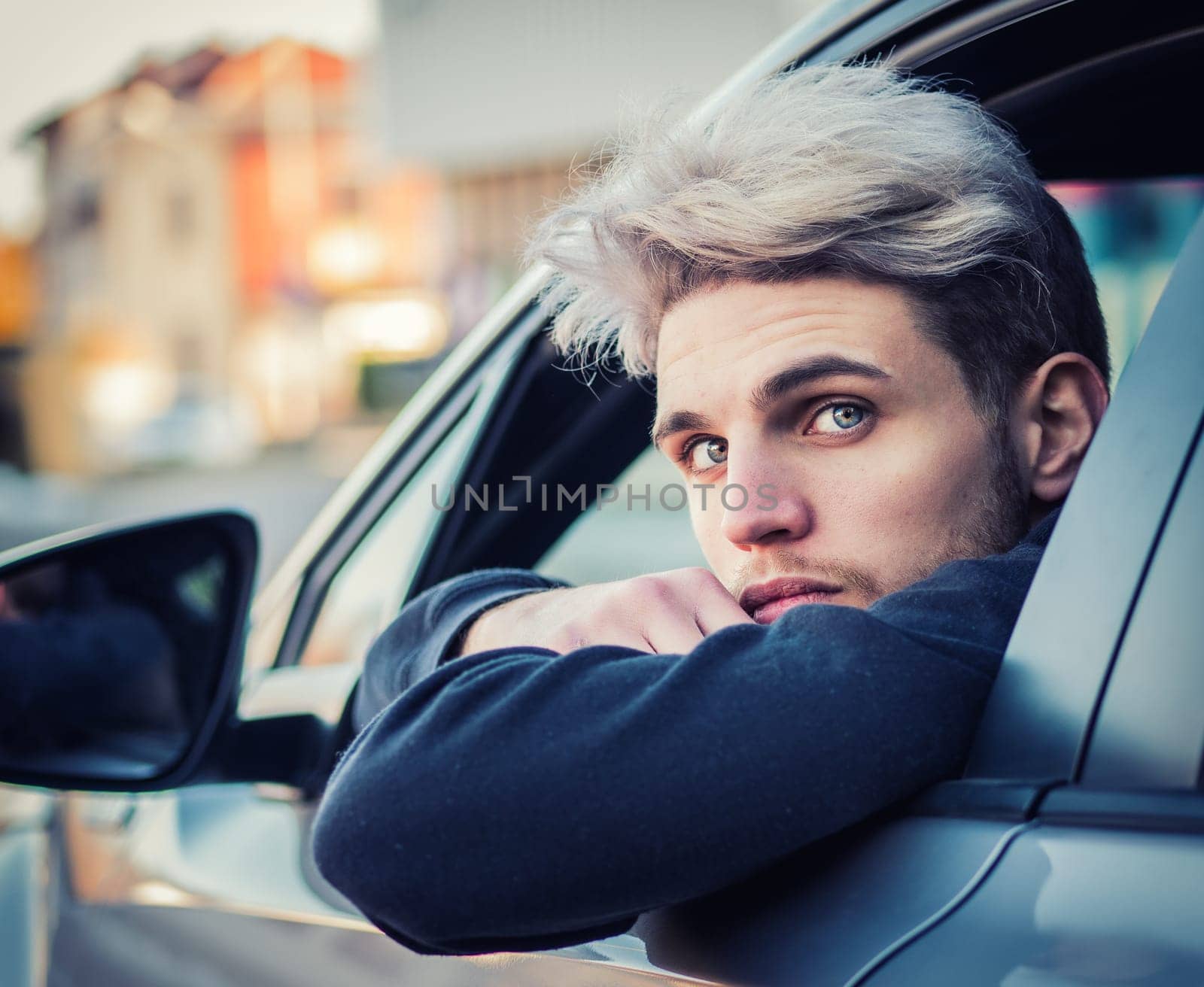 A man leaning his head out of a car window. Photo of a man leaning out of a car window, looking at camera