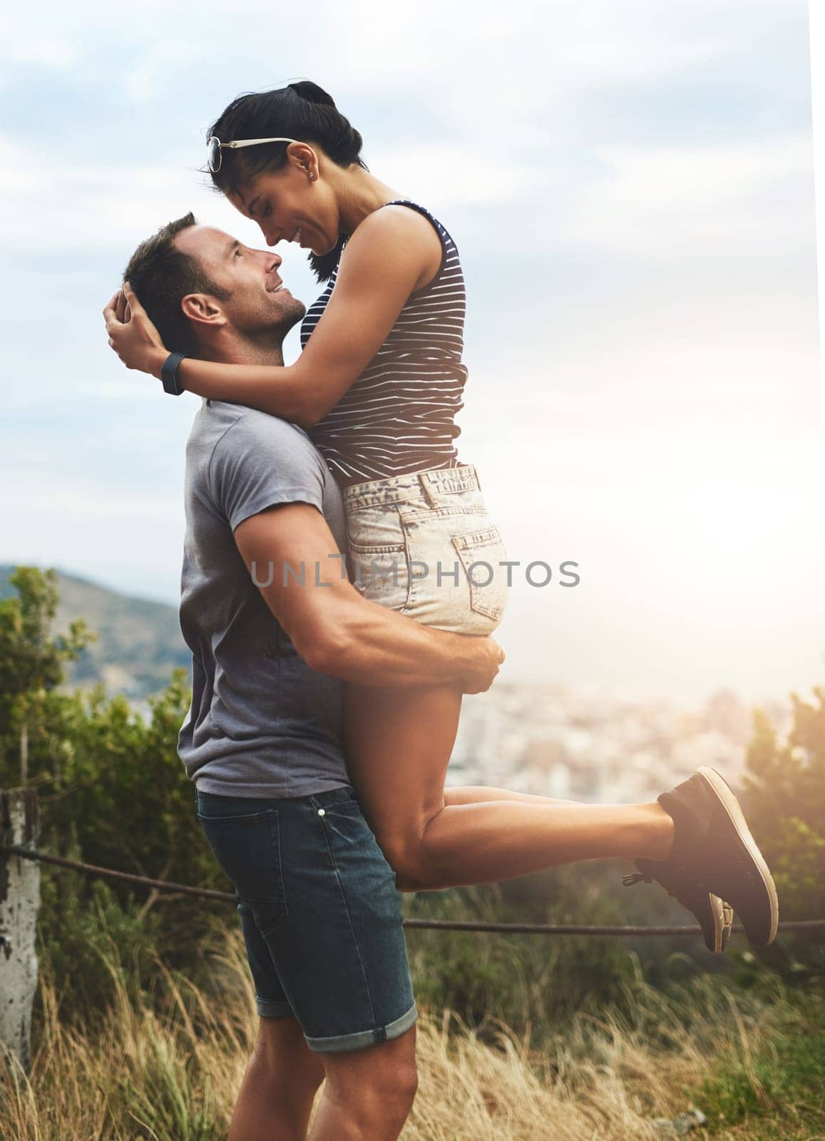 Love, lift or happy couple hug in park for date or care in nature with support, bond or freedom. Eye contact, romantic man or woman excited by holiday vacation together to celebrate, relax or travel.