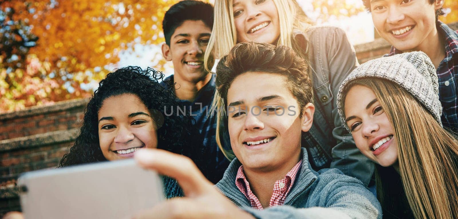 Smile, friends and a selfie in nature for bonding, fun and video call in autumn. Happy, together and diversity of kids taking a photo on technology in a park for social media or live streaming.