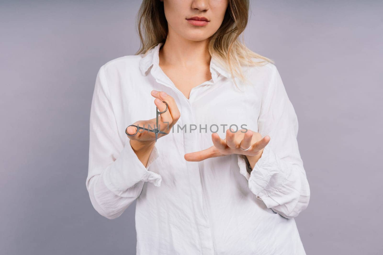 Woman with a scissors having hair cut. Amazed female with straight hair, scissor. Haircare concept.