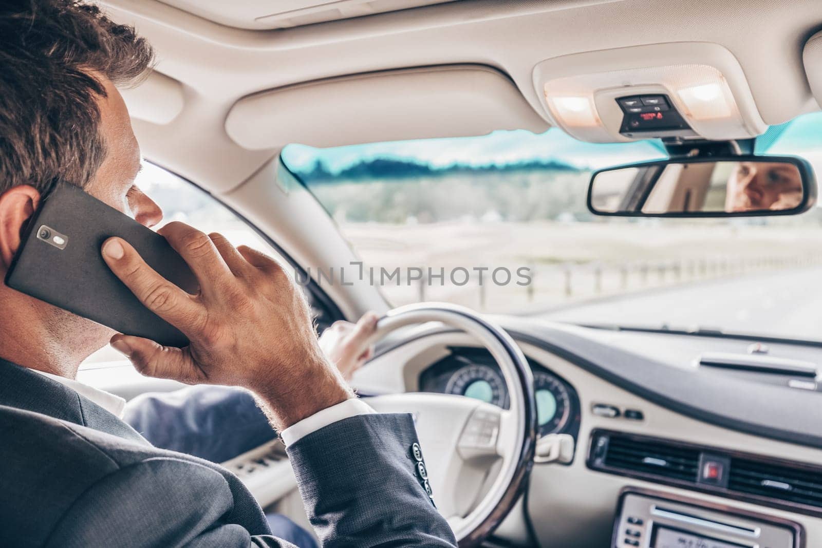 Businessman talking on cell phone while driving and overtaking, not paying attention to the road and traffic.