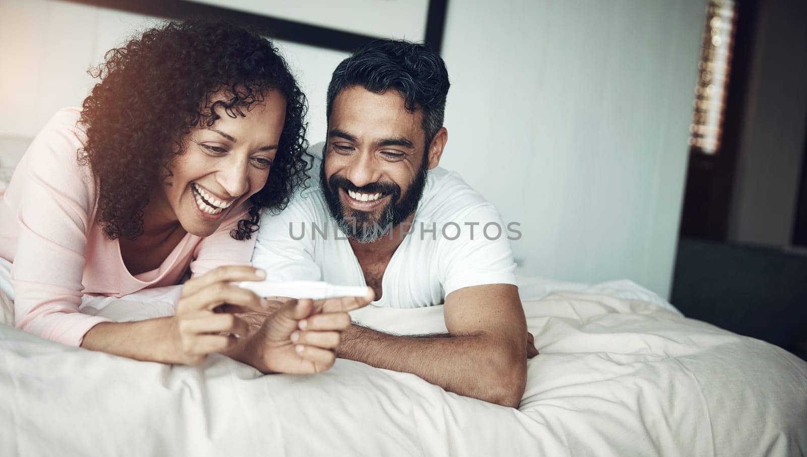 Couple, happy and bedroom with pregnancy test, positive and bed with smile, results and excited. Man, woman and baby with stick, love and maternity for future family, surprise and pregnant together.