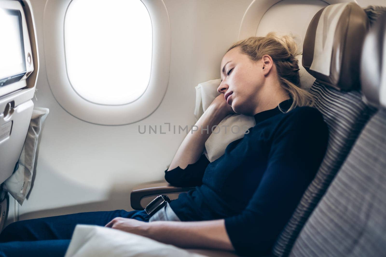 Tired blonde casual caucasian woman napping on airplane. by kasto