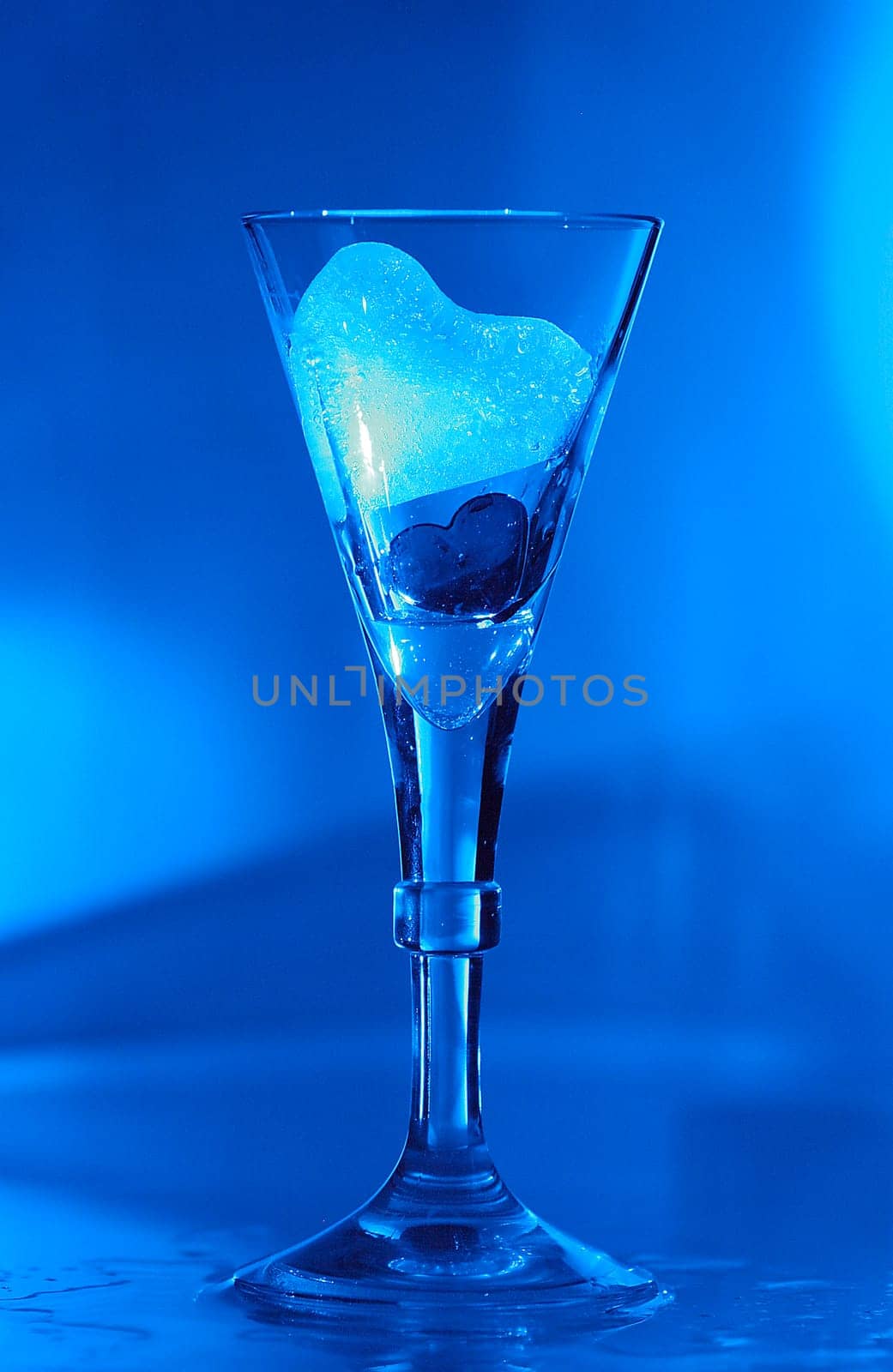 Ice heart and heart in a glass illuminated with blue light.