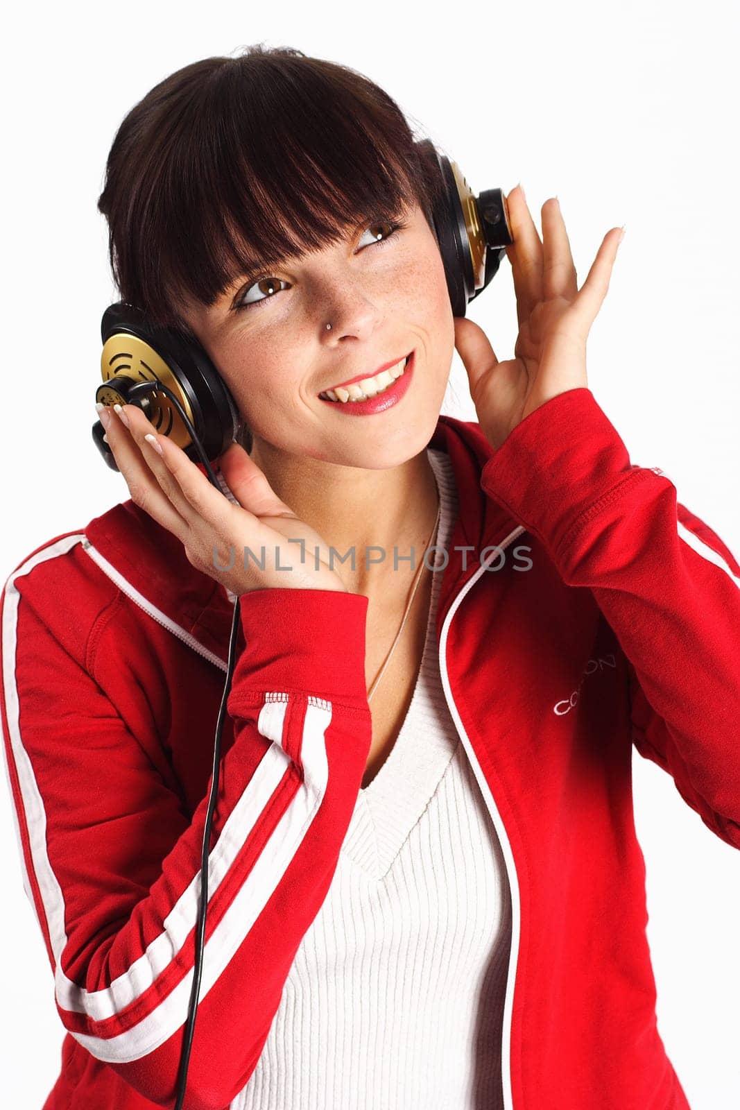 A woman sits smiling with headphones and listening to the music