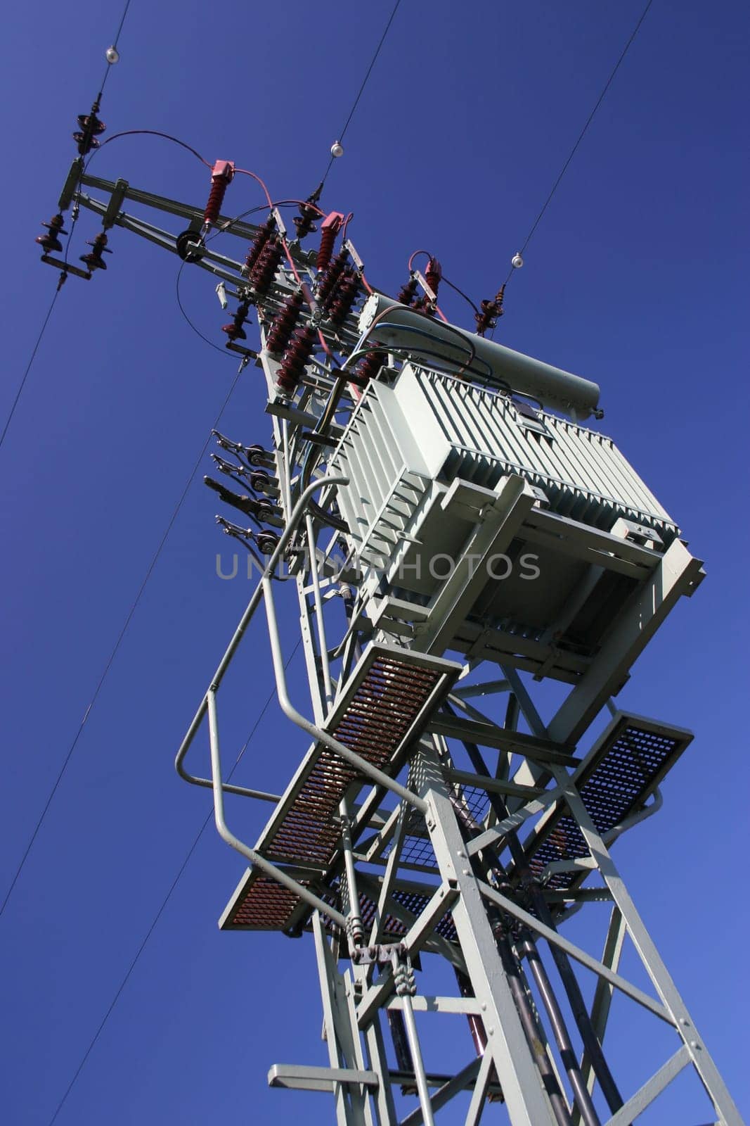 Power pylon with transformer in front of blue sky