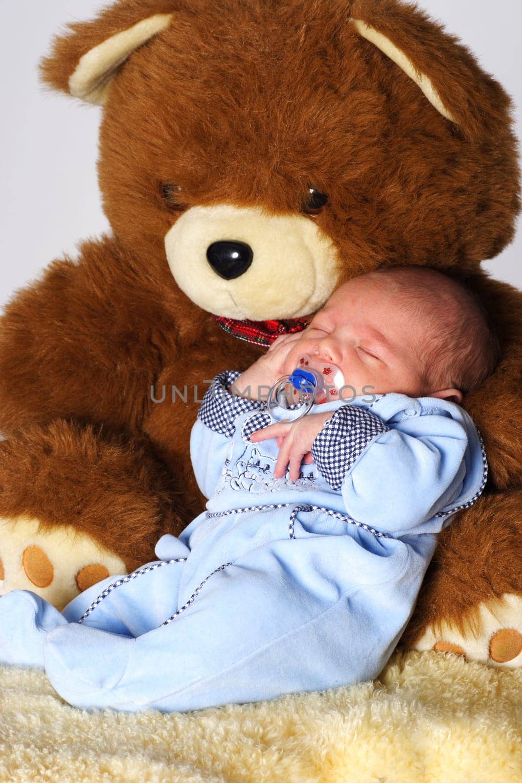Photo shows a sleeping baby with a cuddly toy (bear)