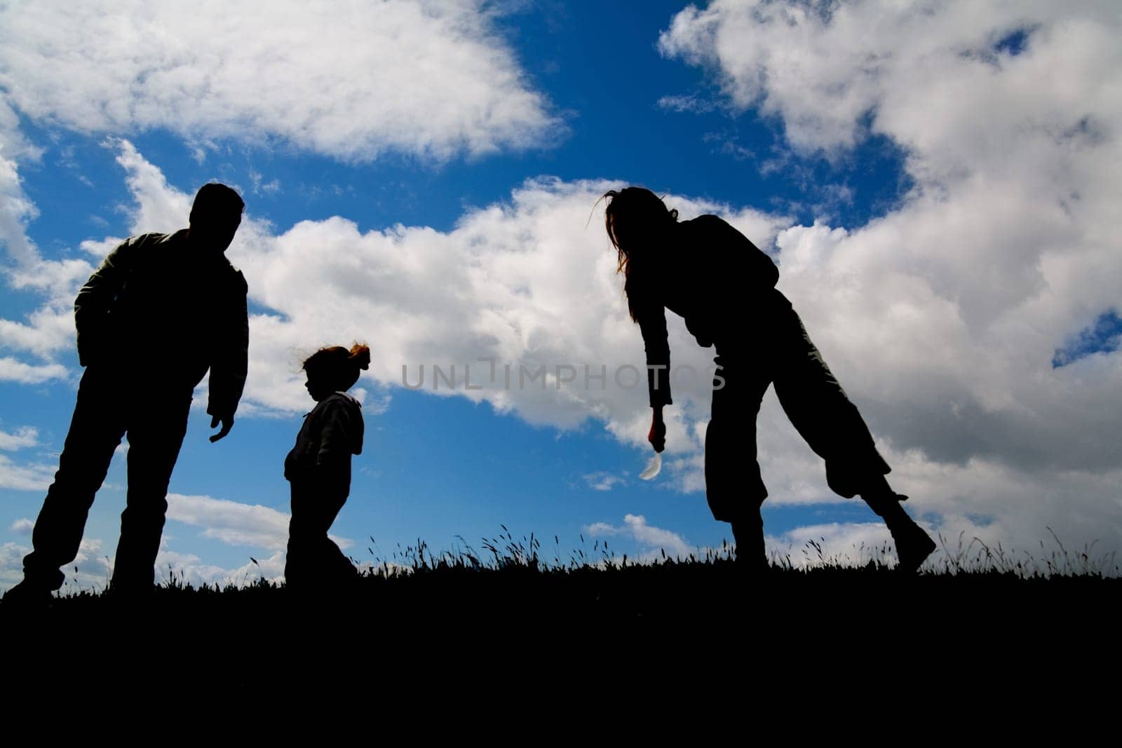Silhouettes of a small family on a hill under backlight