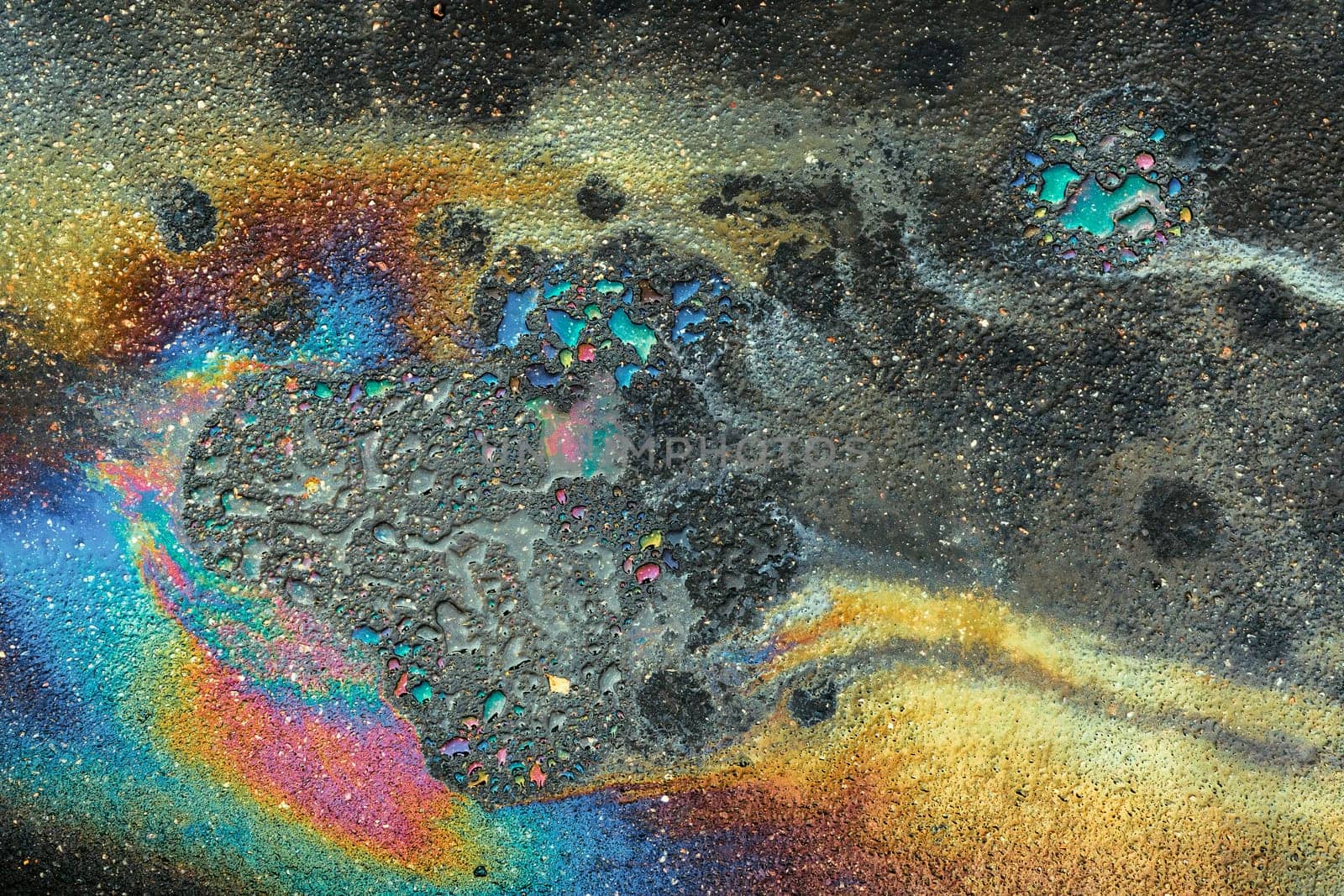 Colored oil stains close-up, color of a gasoline stain on asphalt as a texture or background.