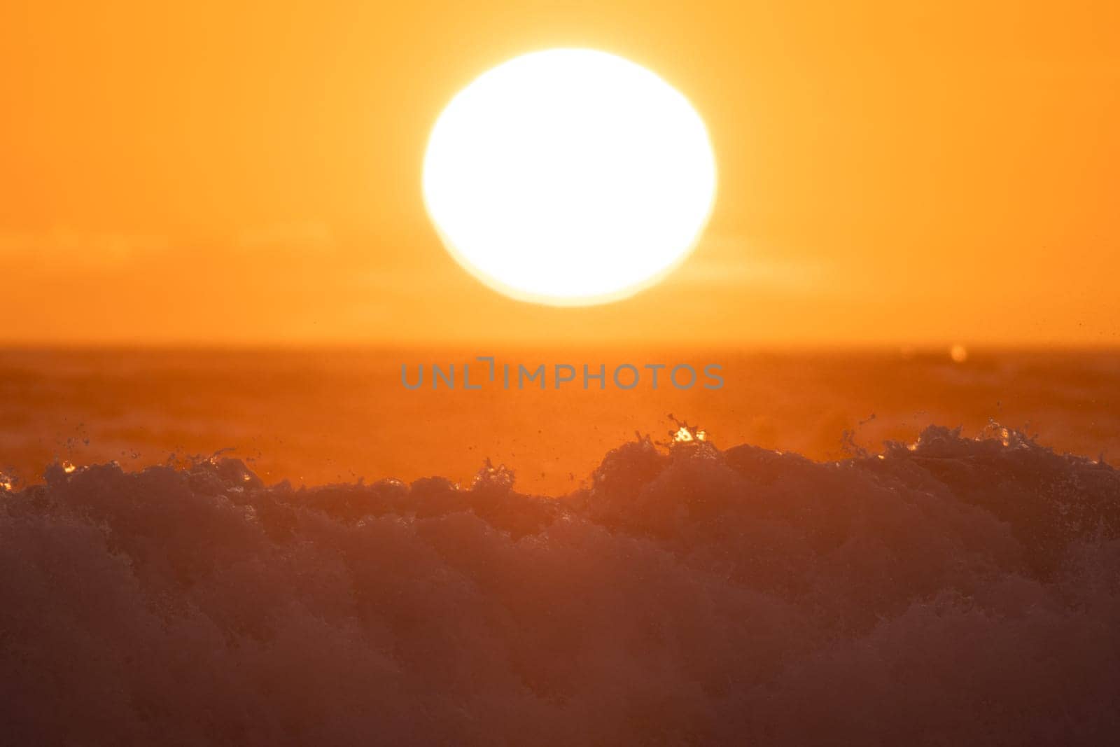 Big sea wave under huge bright sun at orange sunset by Studia72