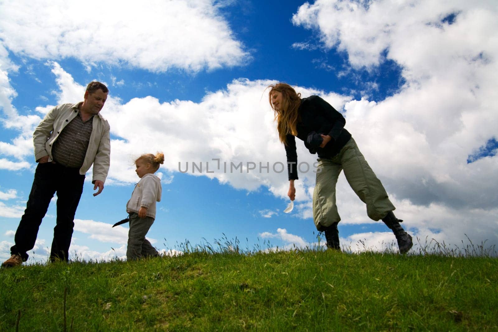 A family on a hill in front of a blue sky with a few clouds