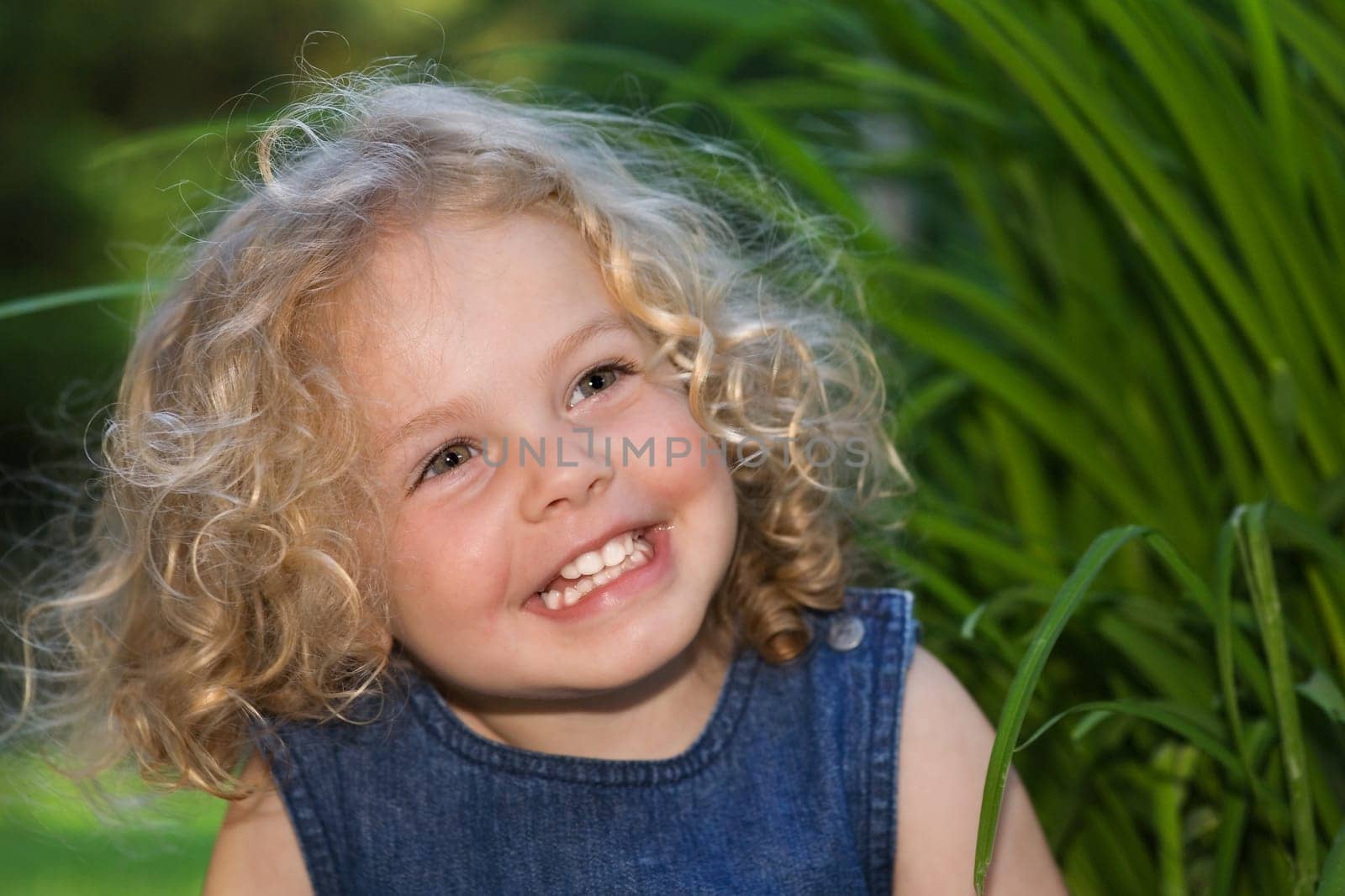 A little pretty girl with curly blond hair laughing