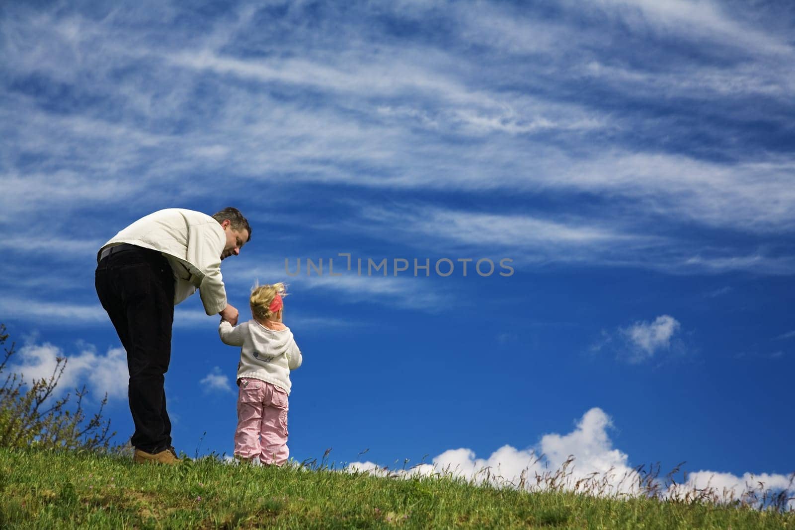 Father and daughter on a hill and looking into the distance,the father seems to explain something to the daughter