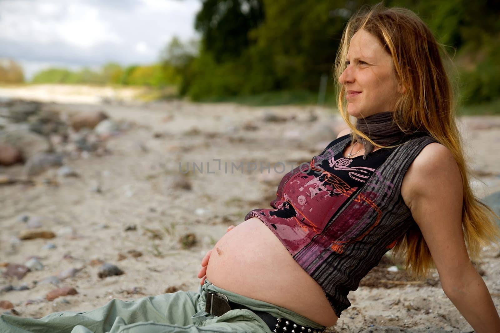 Young pregnant woman sitting relaxed on the beach