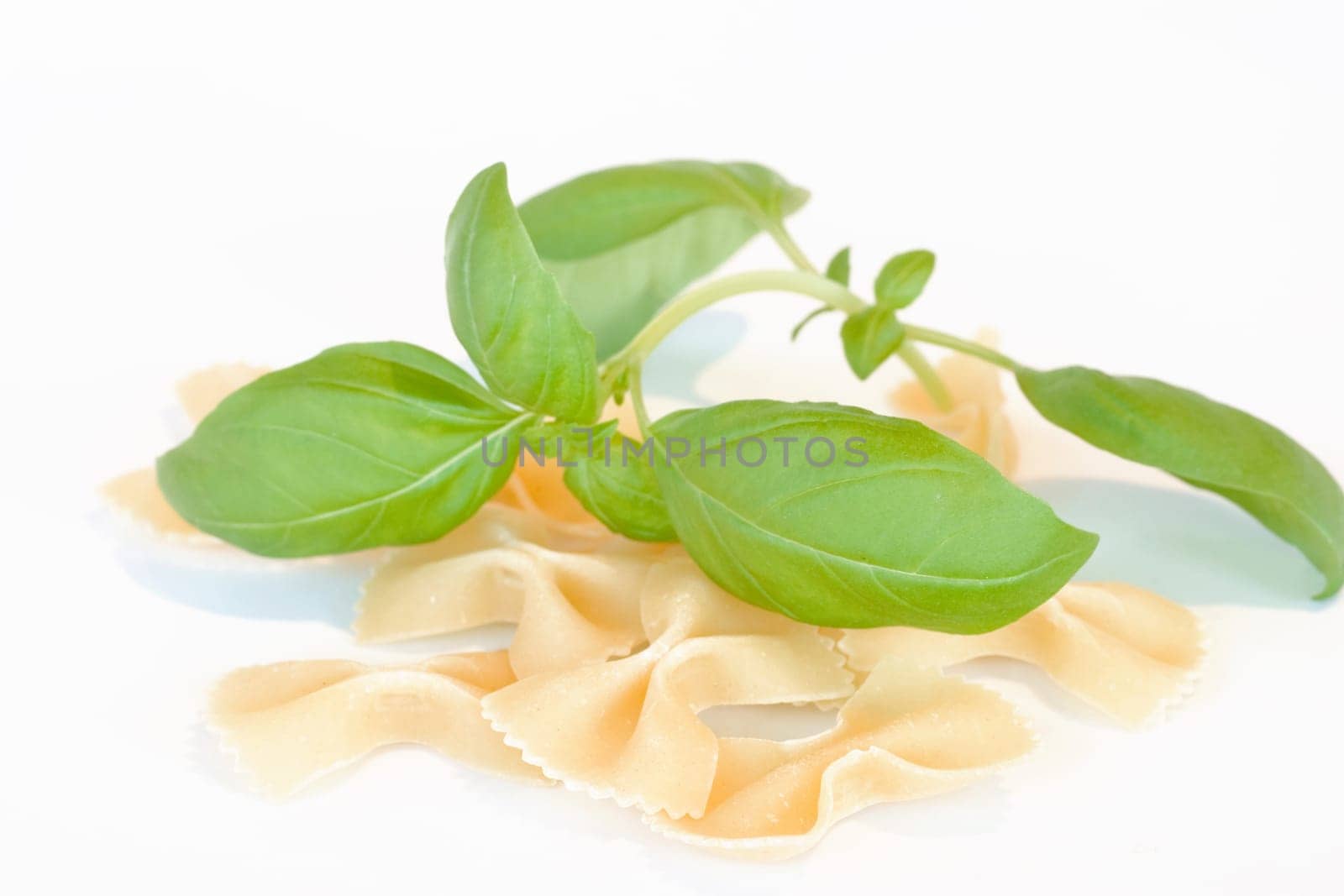 Farfalle on white background with basil